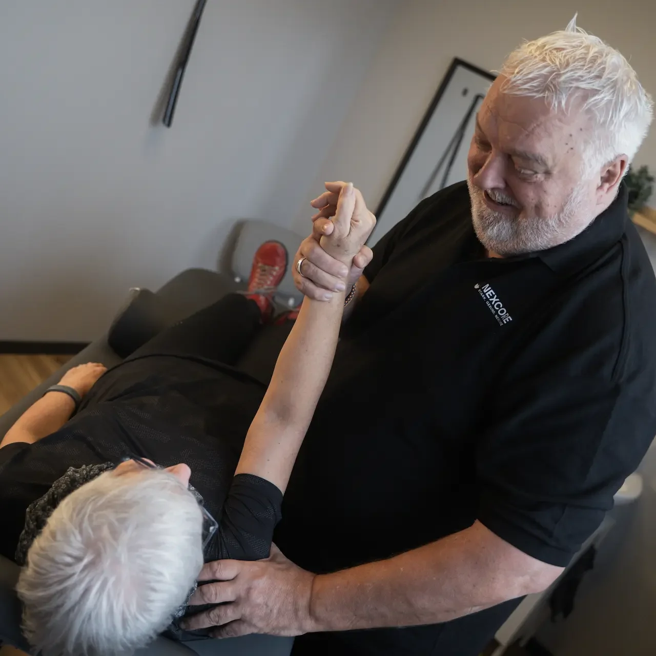 Therapeut begleitet einen Patienten bei aktiven Reha-Übungen im NEXCORE Trainingsbereich.